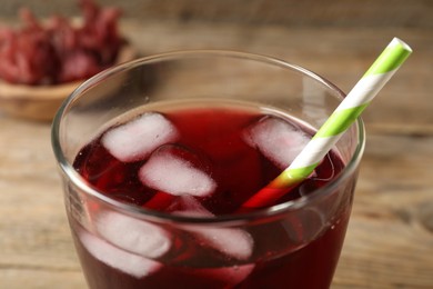 Photo of Glass of delicious iced hibiscus tea with straw against blurred background, closeup