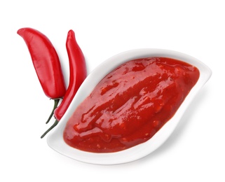 Photo of Gravy boat with red sauce and fresh chili peppers isolated on white, top view