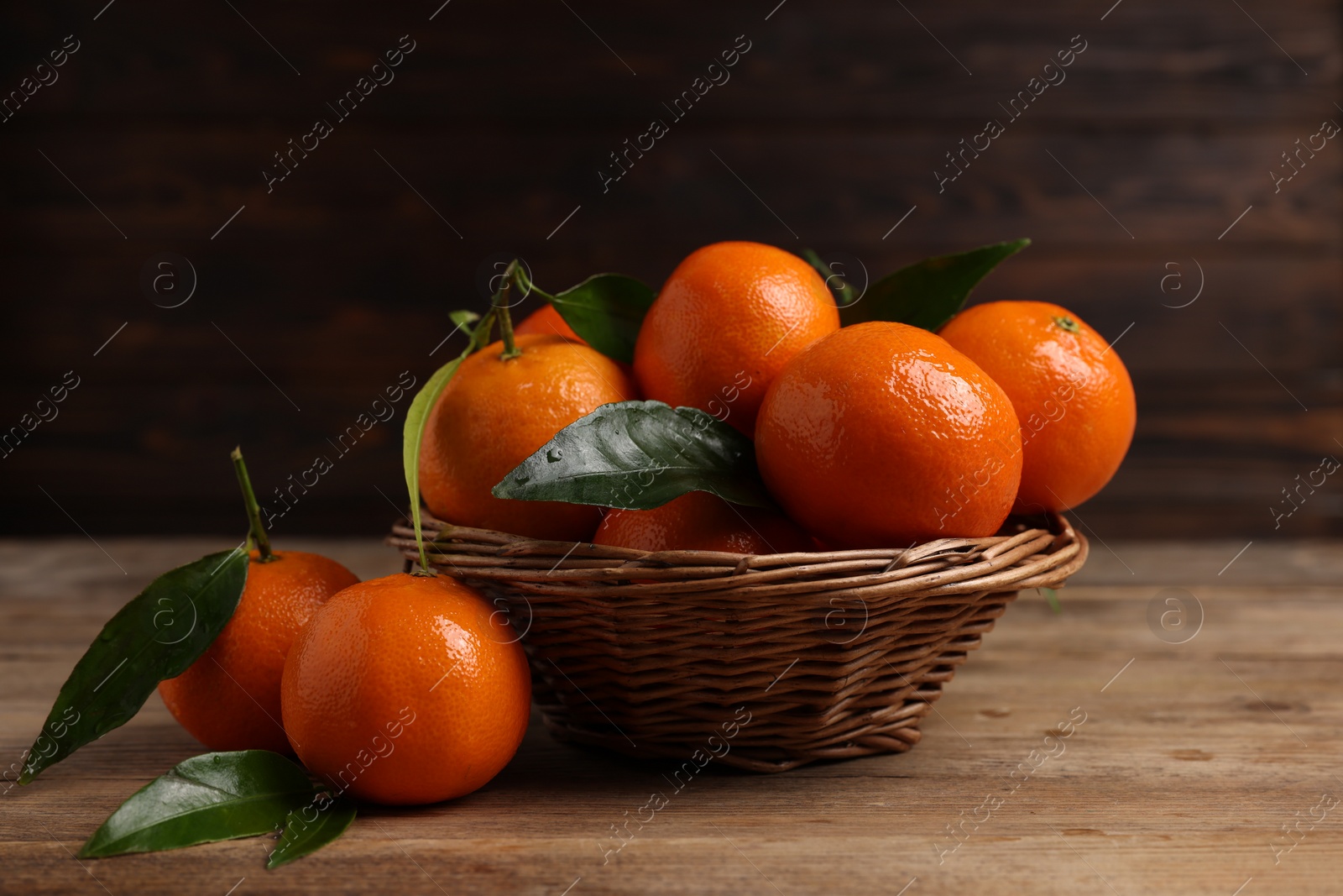 Photo of Delicious tangerines with leaves on wooden table, closeup