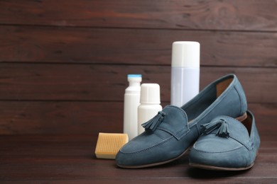 Stylish footwear with shoe care accessories on brown wooden table. Space for text
