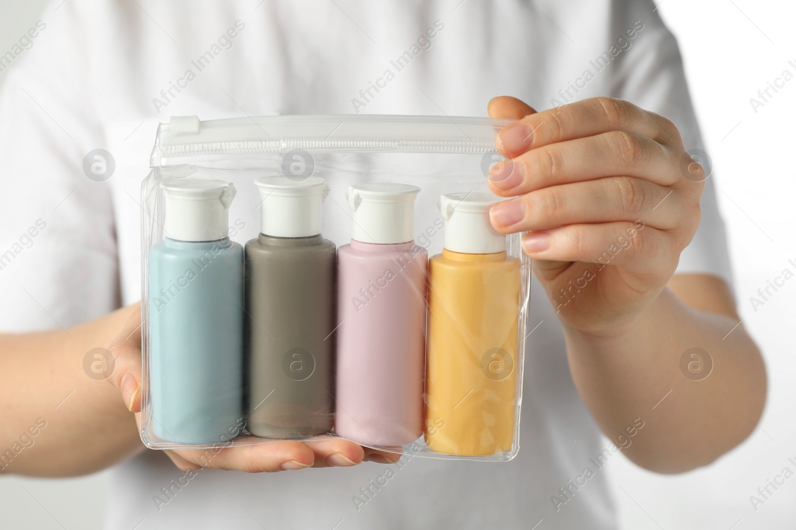 Photo of Woman with cosmetic travel kit on white background, closeup