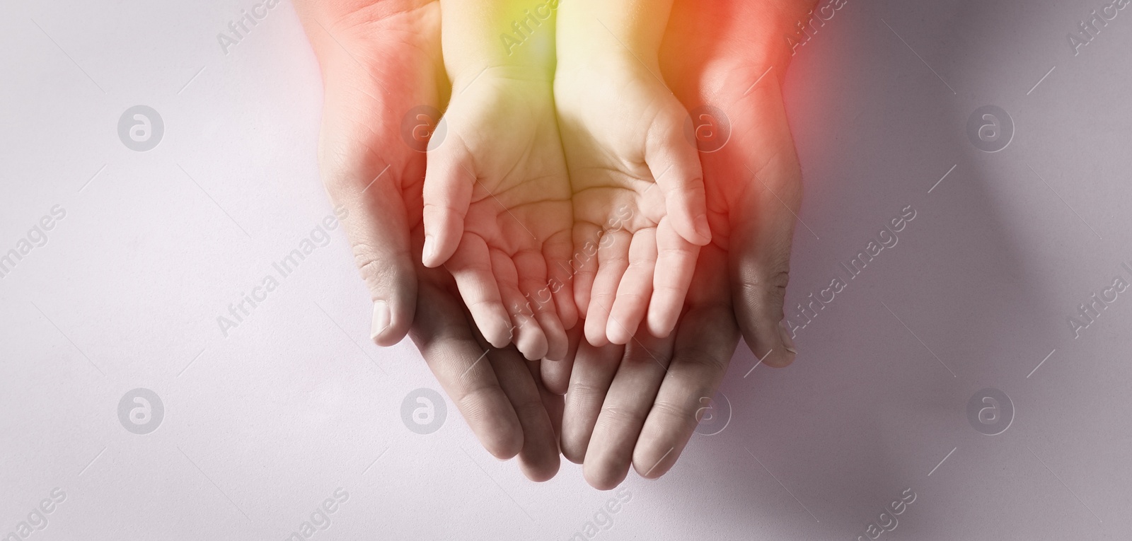 Image of Mother holding hands with her child on light background, top view. Banner design 