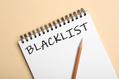 Image of Word Blacklist written in notepad on beige background, top view