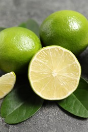 Fresh ripe limes and leaves on grey table, closeup