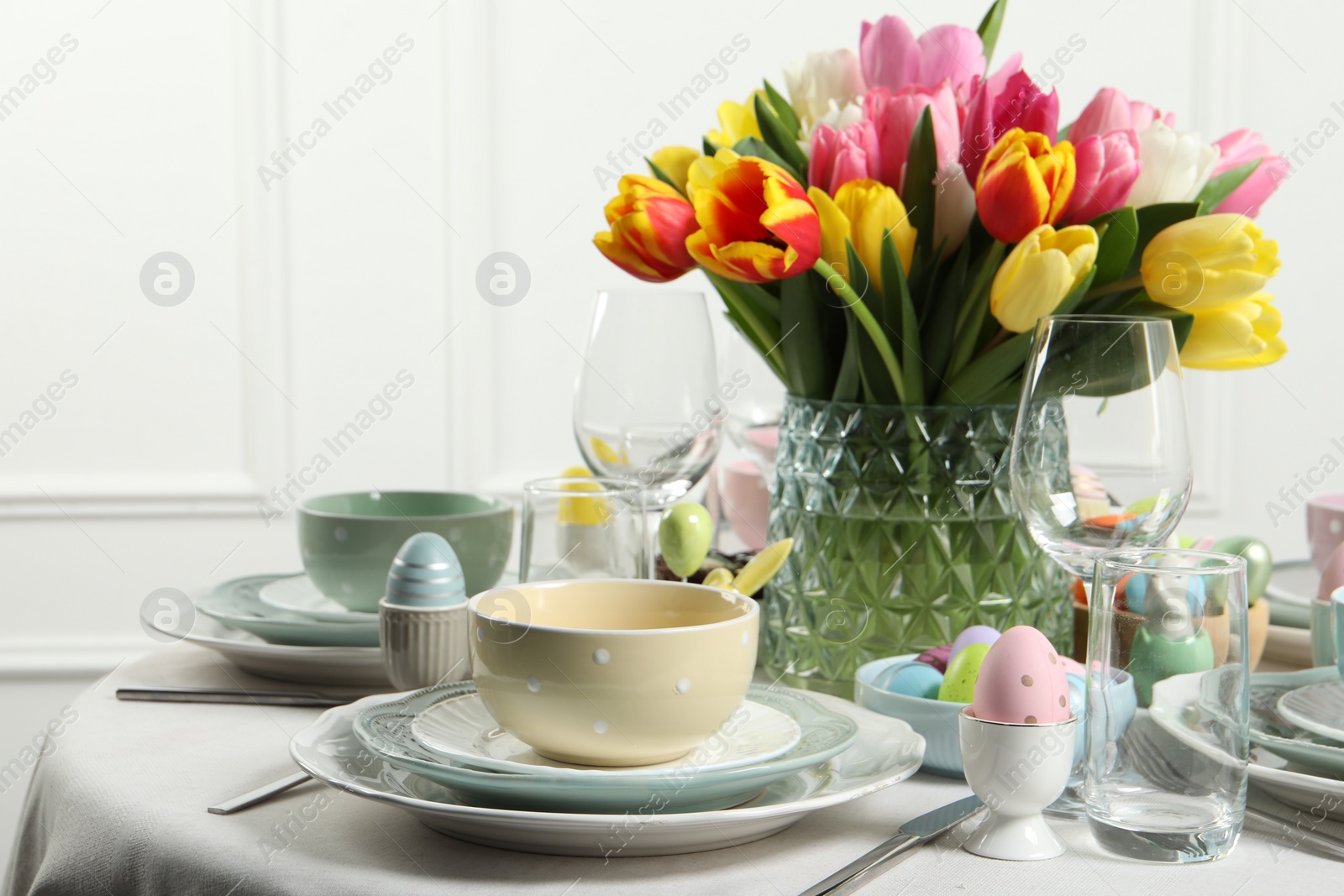 Photo of Easter celebration. Festive table setting with beautiful flowers and painted eggs