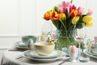 Photo of Easter celebration. Festive table setting with beautiful flowers and painted eggs