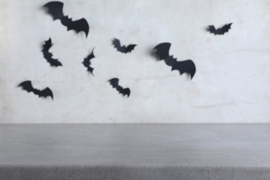 Stone table near grey wall with black paper bats. Halloween decoration