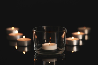 Wax candles burning on table in darkness