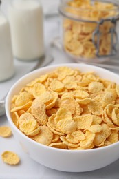 Photo of Tasty crispy corn flakes in bowl on white table, closeup. Breakfast cereal