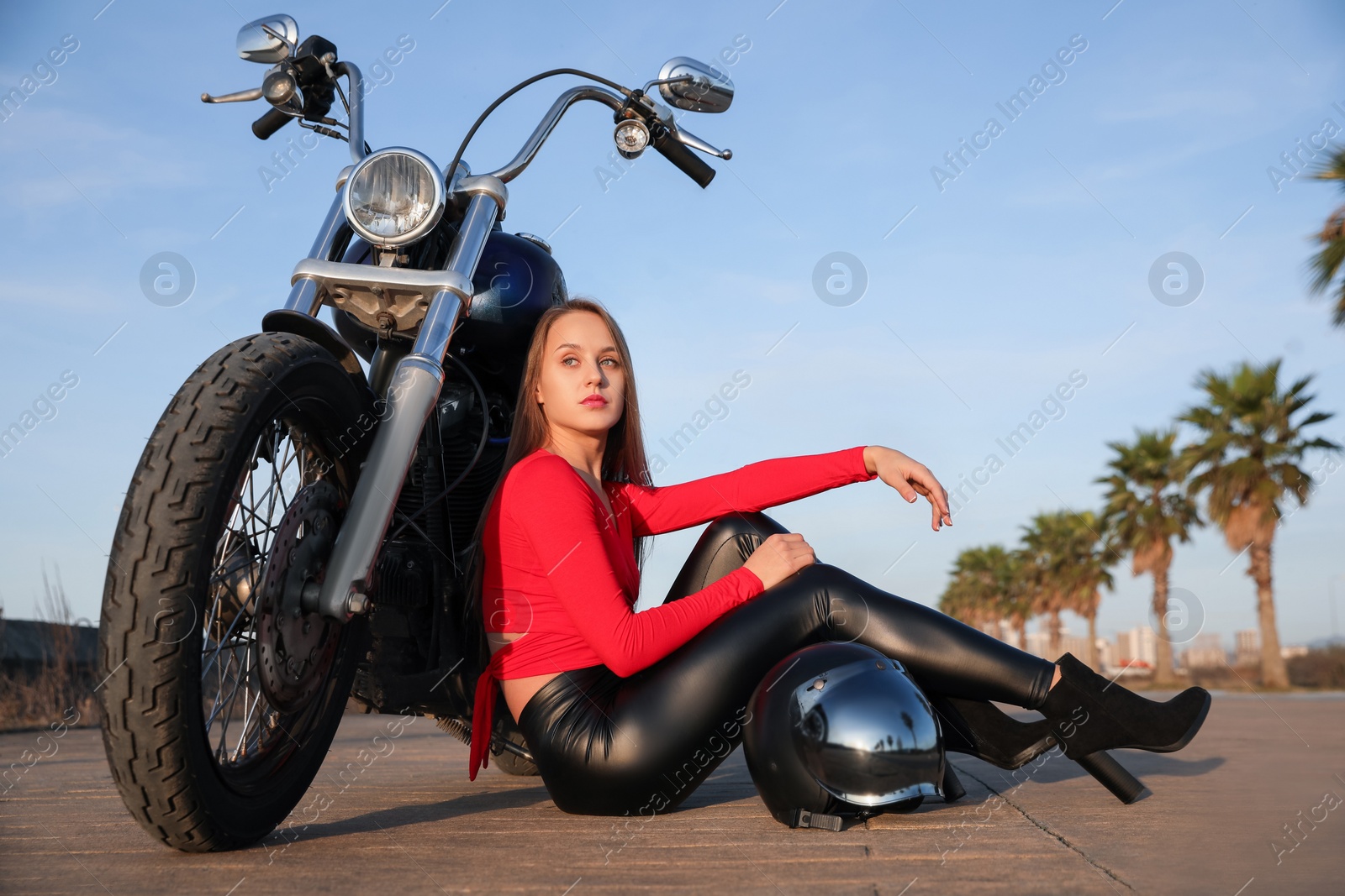 Photo of Attractive woman sitting with helmet near motorcycle on sunny day