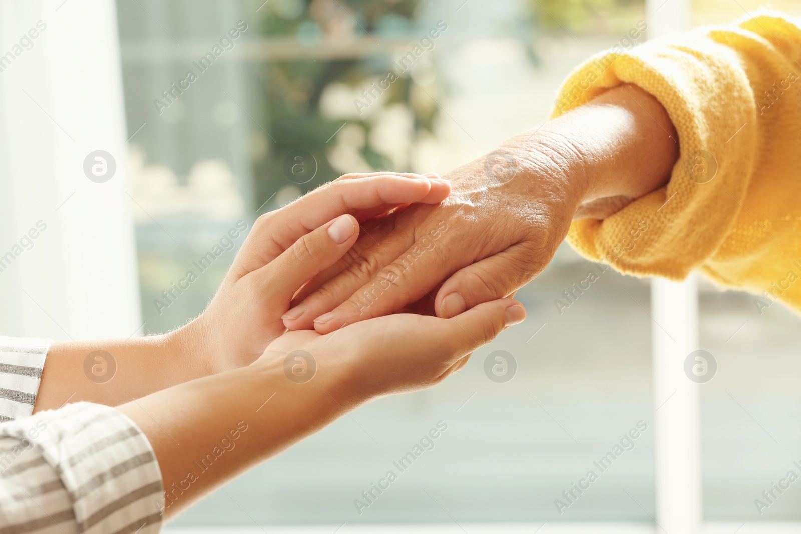 Photo of Helping hands on blurred background, closeup. Elderly care concept