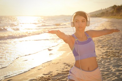 Photo of Young woman doing yoga on beach at sunset
