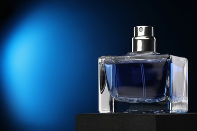 Photo of Luxury men`s perfume in bottle against dark blue background, space for text