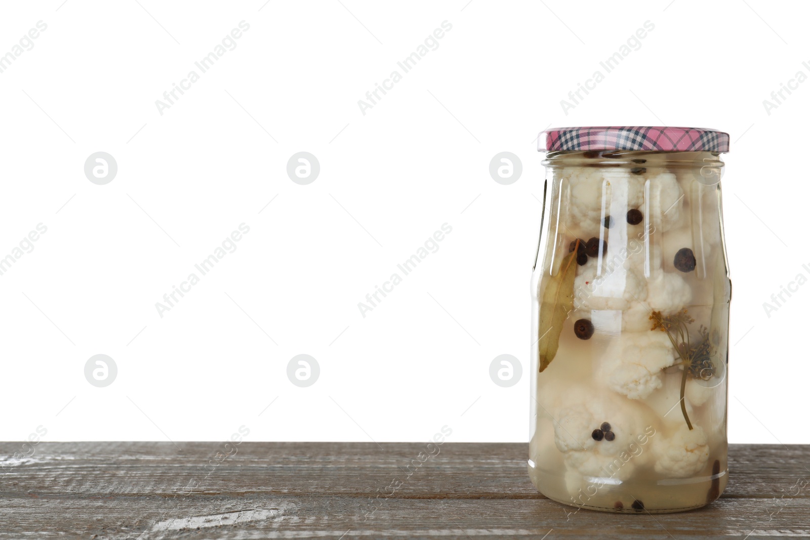 Photo of Jar of pickled cauliflowers on wooden table against white background. Space for text