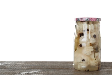 Photo of Jar of pickled cauliflowers on wooden table against white background. Space for text