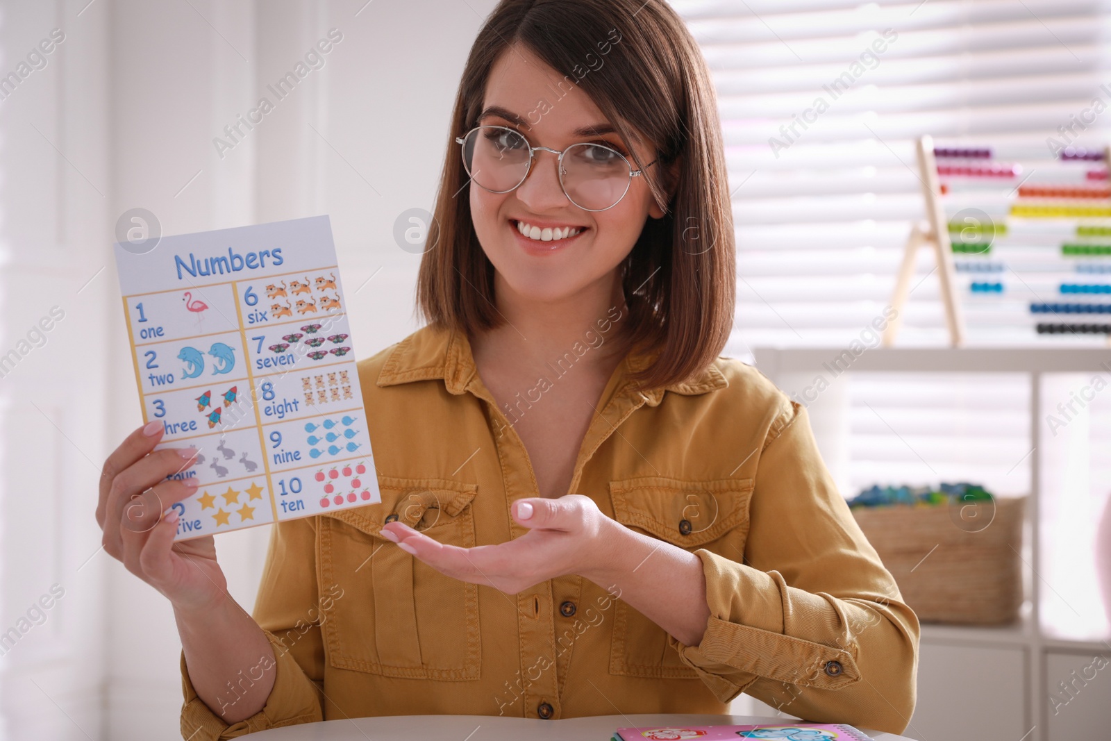 Photo of Happy female English teacher giving lesson indoors. Early childhood education