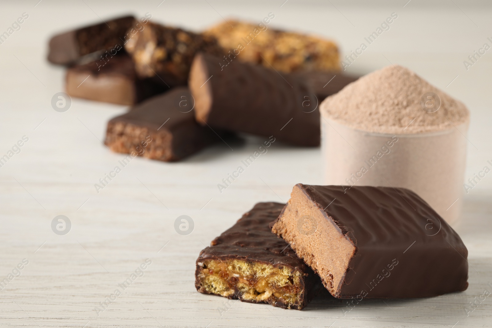 Photo of Different tasty energy bars and protein powder on white table, closeup. Space for text