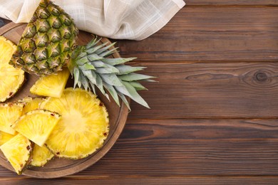 Photo of Pieces of tasty ripe pineapple on wooden table, top view. Space for text