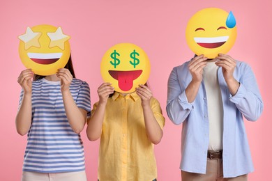 Photo of People covering faces with emoticons on pink background