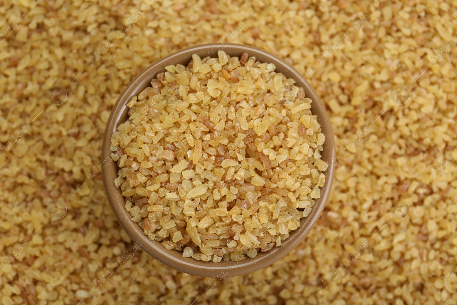 Photo of Bowl on pile of uncooked bulgur, top view