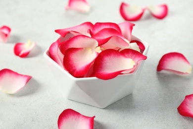 Photo of Bowl with rose petals on light background