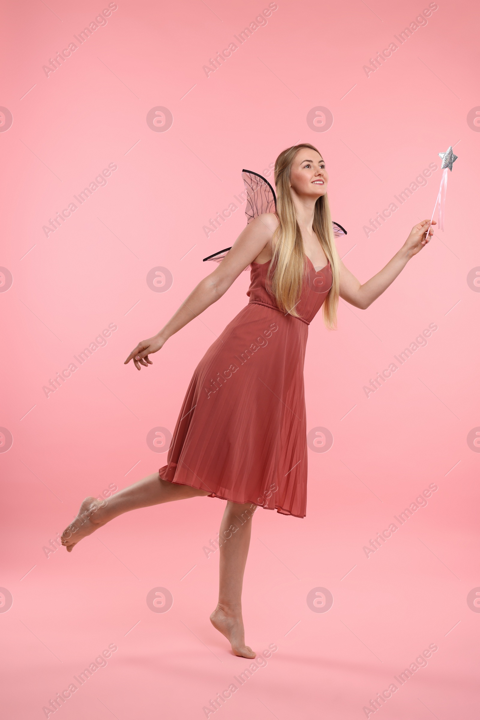 Photo of Beautiful girl in fairy costume with wings on pink background