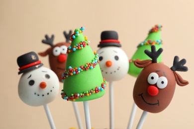 Delicious Christmas themed cake pops on beige background, closeup