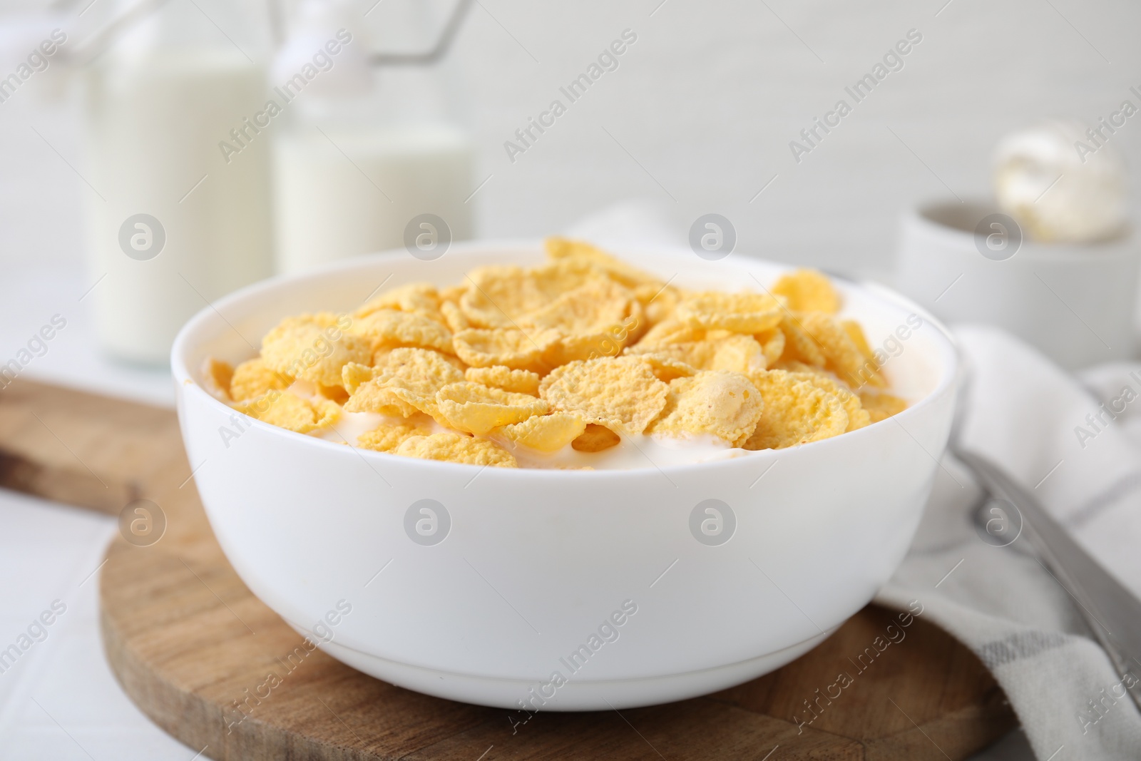 Photo of Breakfast cereal. Tasty corn flakes with milk in bowl on white table, closeup