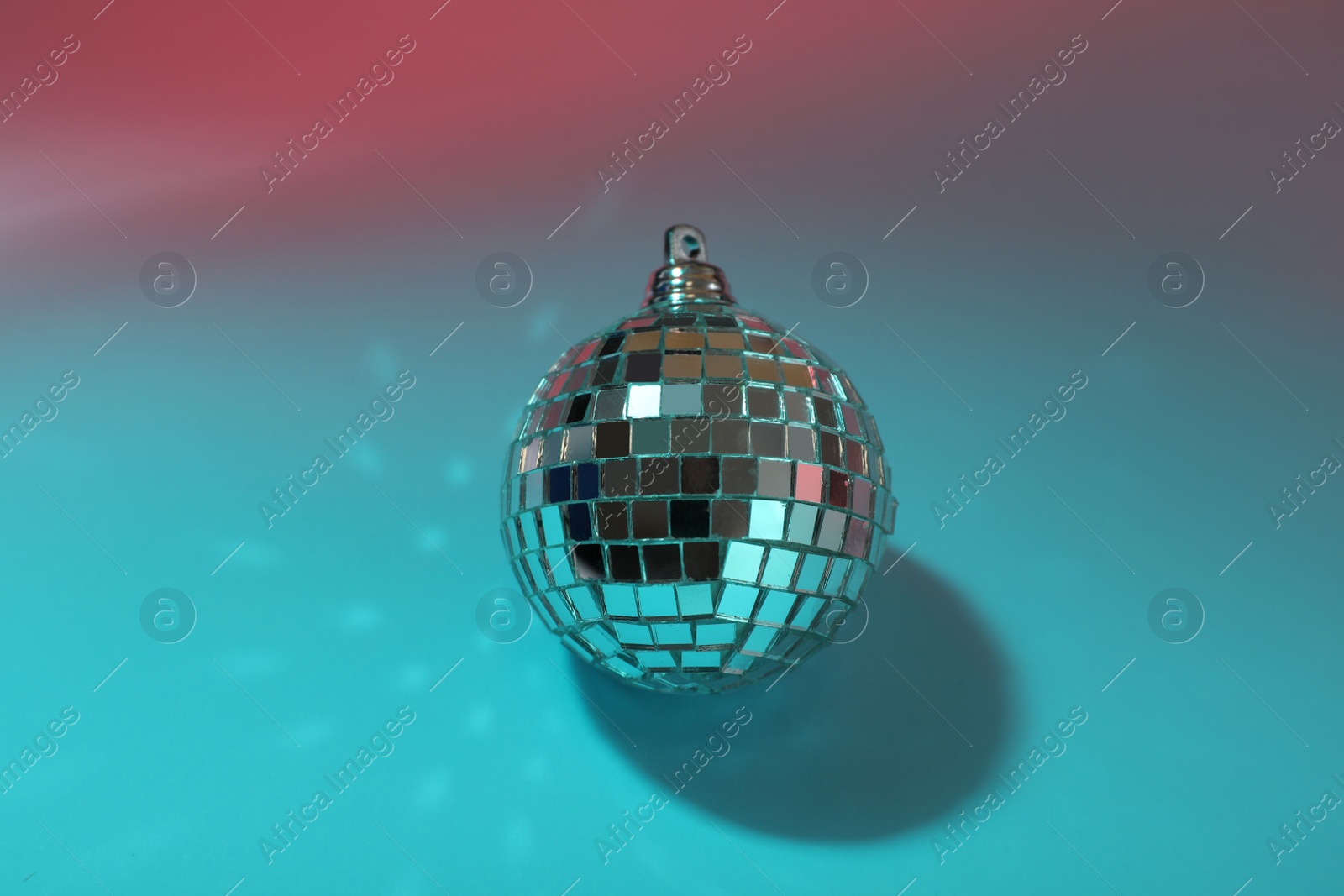 Photo of Bright shiny disco ball on color background