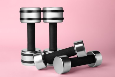 Photo of Dumbbells on light pink background. Weight training equipment