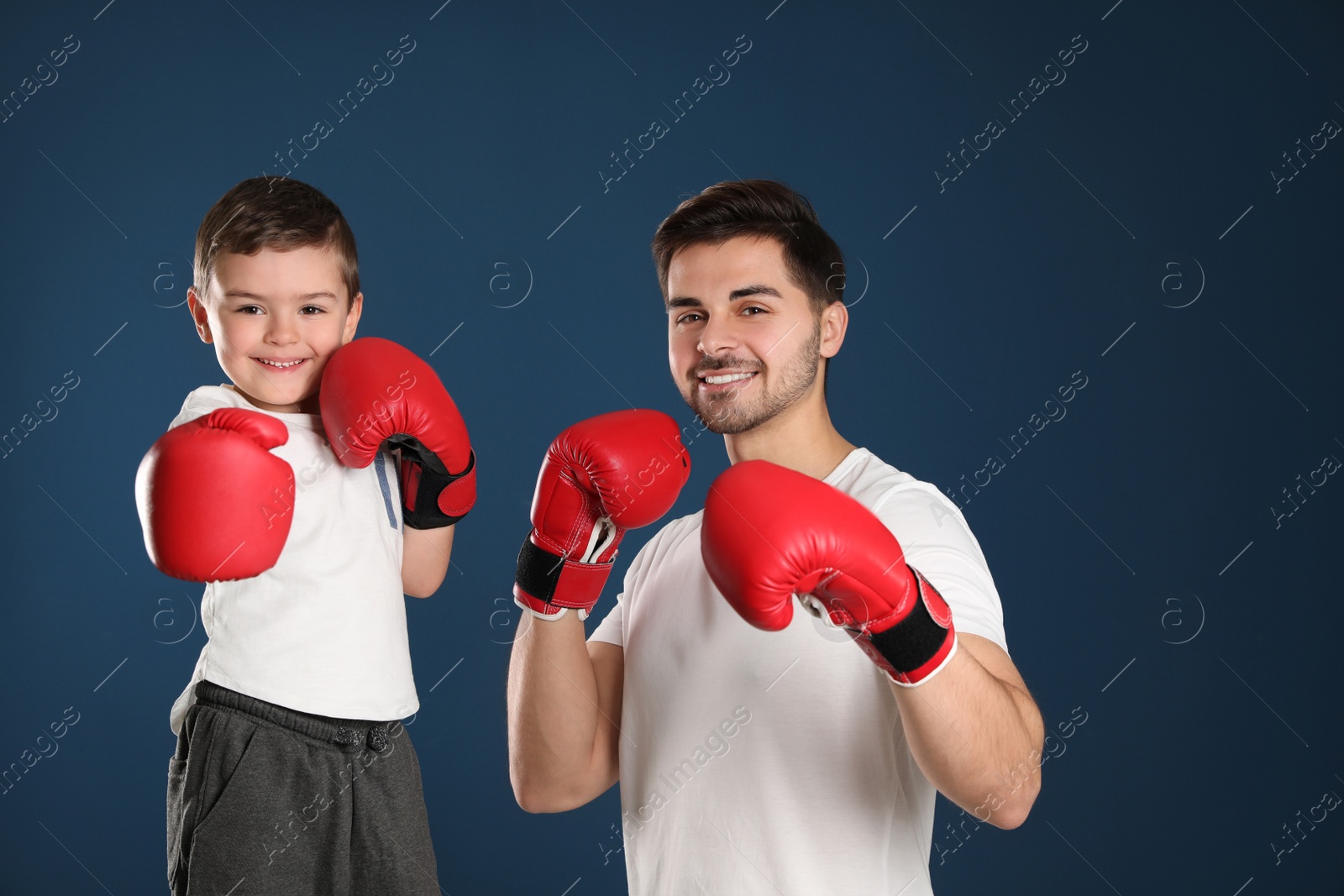 Photo of Dad and his son with boxing gloves on color background