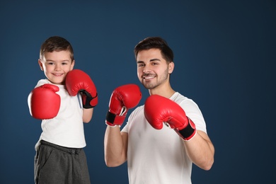 Photo of Dad and his son with boxing gloves on color background