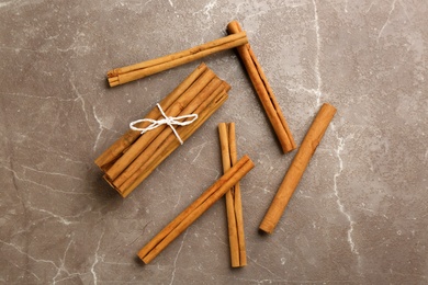 Aromatic cinnamon sticks on grey table, flat lay