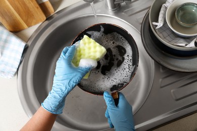 Photo of Woman washing dirty frying pan in sink, above view