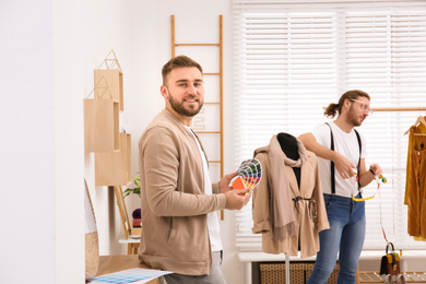 Photo of Fashion designer with colleague creating new clothes in studio