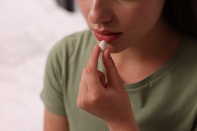 Woman taking antidepressant pill on blurred background, closeup