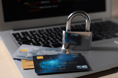 Photo of Credit cards, lock and laptop on table, closeup. Cyber crime