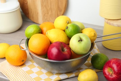 Photo of Metal colander with different fruits on table, closeup