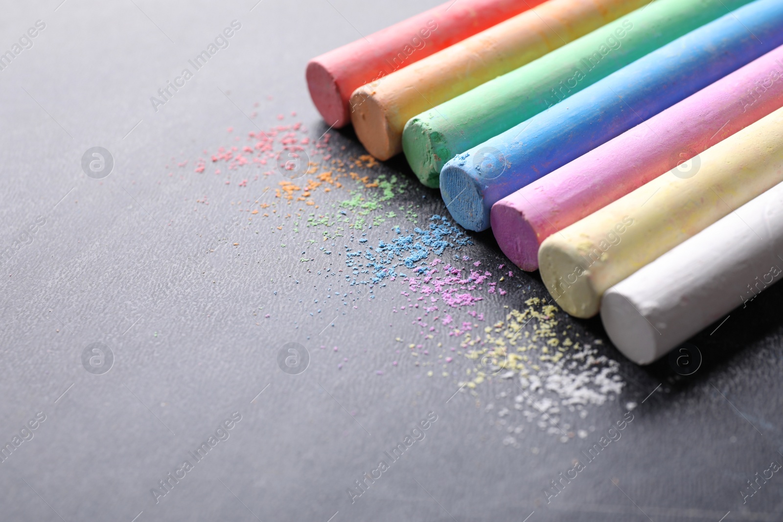 Photo of Pieces of color chalk on blackboard, space for text