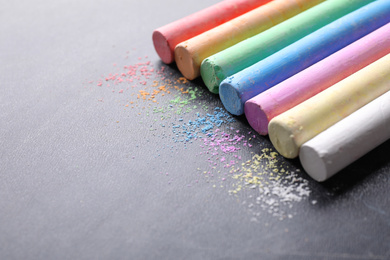 Photo of Pieces of color chalk on blackboard, space for text