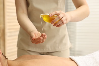 Photo of Aromatherapy. Woman receiving back massage with oil in spa salon, closeup