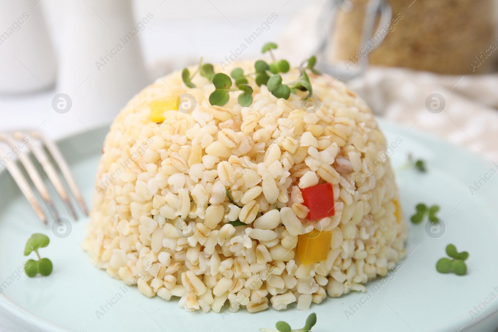 Photo of Delicious bulgur with vegetables and microgreens on table, closeup