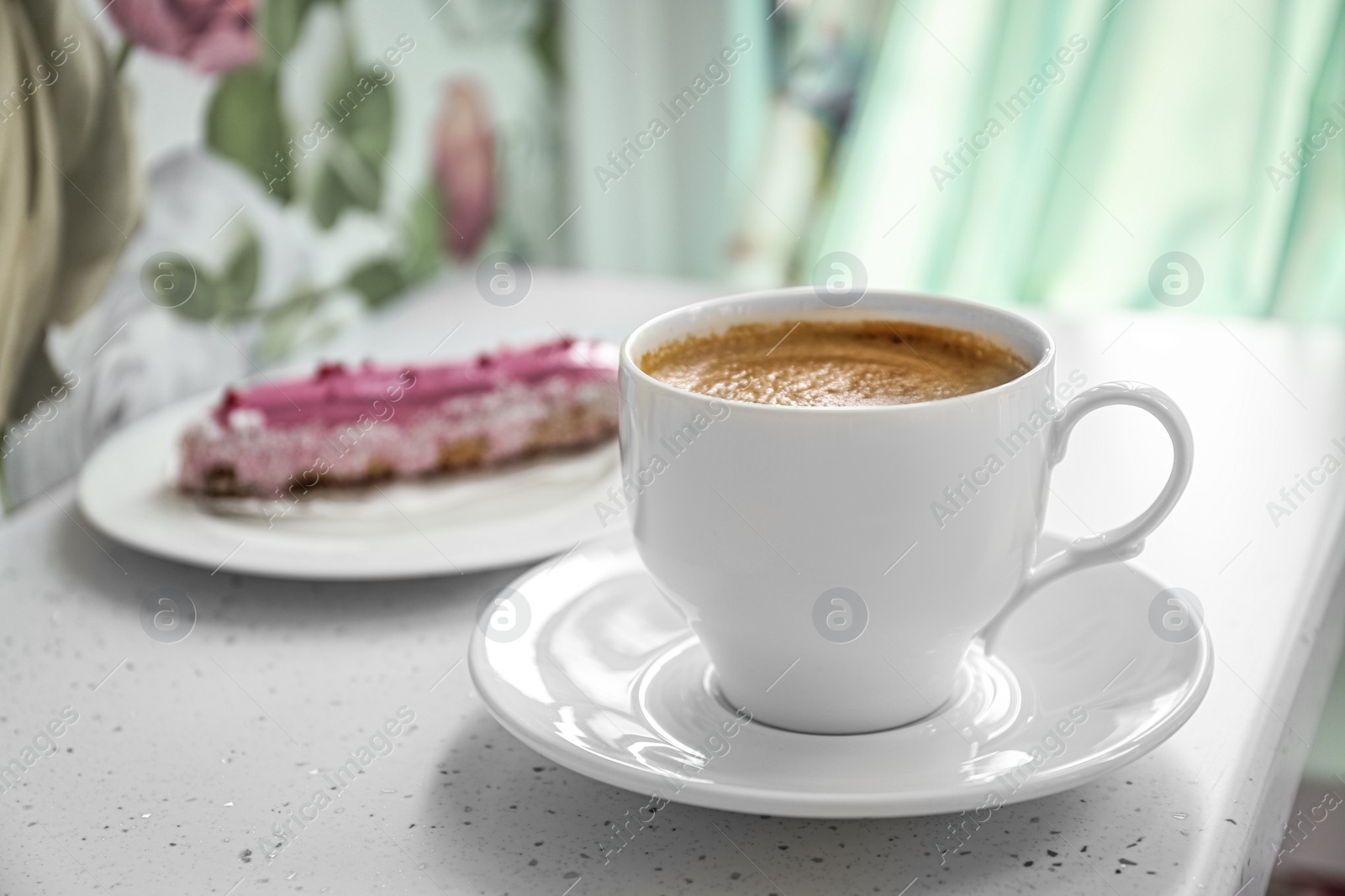 Photo of Cup of delicious aromatic coffee and eclair on white table indoors, closeup