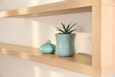 Photo of Wooden shelf with houseplant on light wall