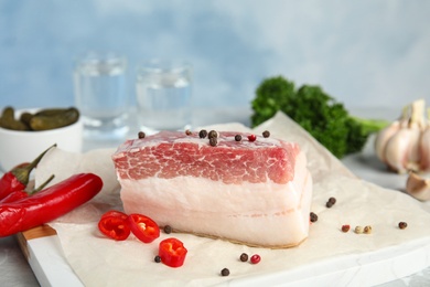 Photo of Composition with pork fatback and spices on white table against blue background