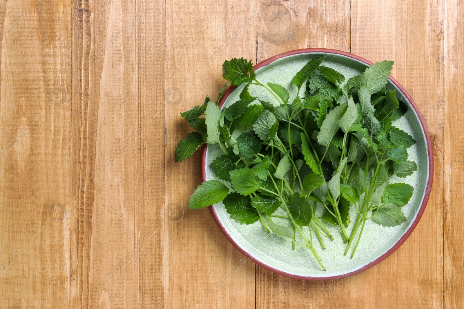 Photo of Fresh lemon balm on wooden table, top view. Space for text