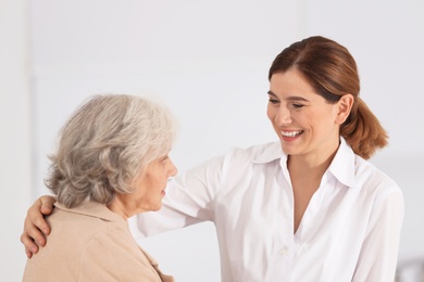 Photo of Elderly woman with nurse on light background
