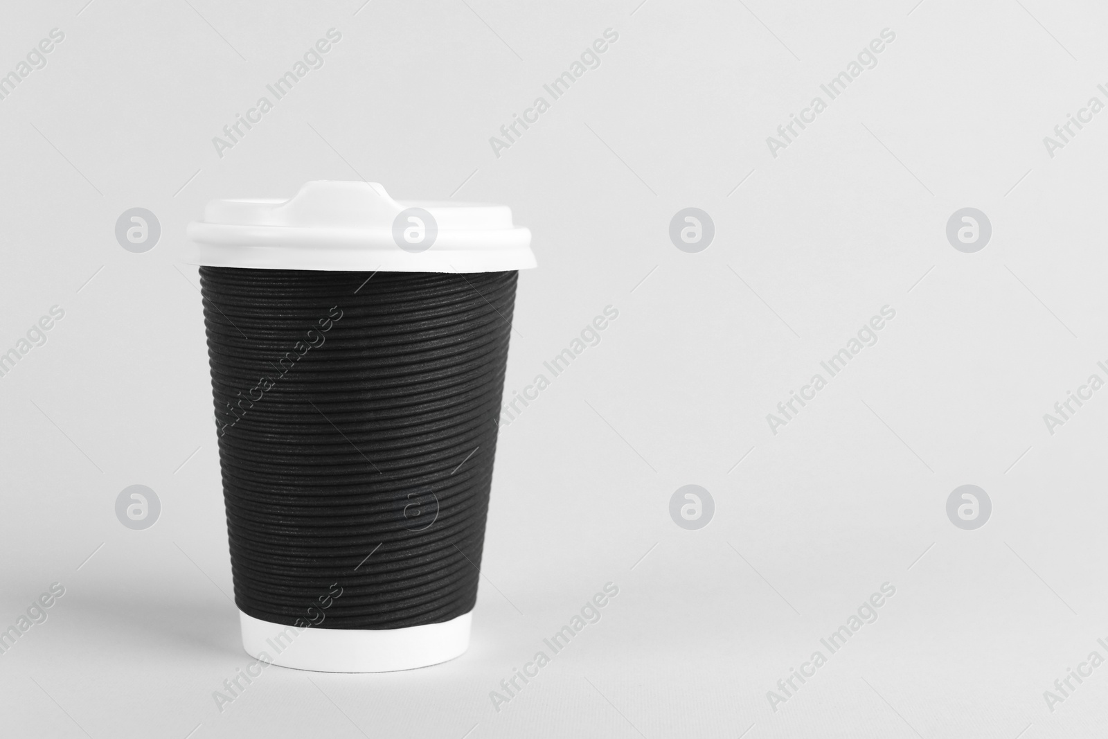 Photo of Black paper cup with plastic lid on light background, space for text. Coffee to go