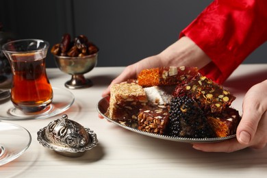 Photo of Woman serving Turkish delight on vintage tray, closeup