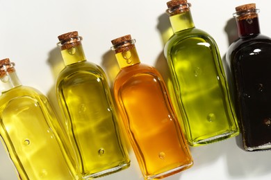 Vegetable fats. Different cooking oils in glass bottles on white background, flat lay